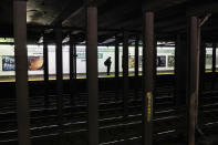 A solitary subway customer stands on an empty platform in the morning hours as COVID-19 concerns drives down public gatherings, Thursday, March 19, 2020, in New York. As of Sunday, nearly 2,000 people with the virus have been hospitalized in the state of New York and 114 have died, officials said. More than 15,000 have tested positive statewide, including 9,000 in New York City. (AP Photo/John Minchillo)