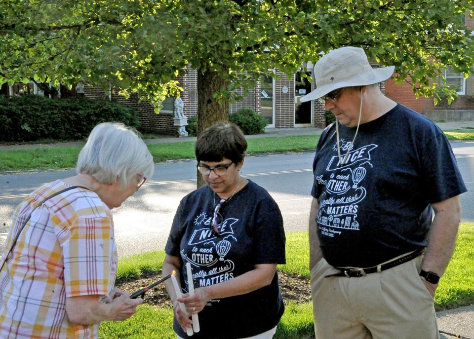 Janet Burkhart lights candles for Cheryl and Mark Gooch at the Central Christian Church Vigil in Wooster Tuesday in honor of the school shooting victims in Uvalde.