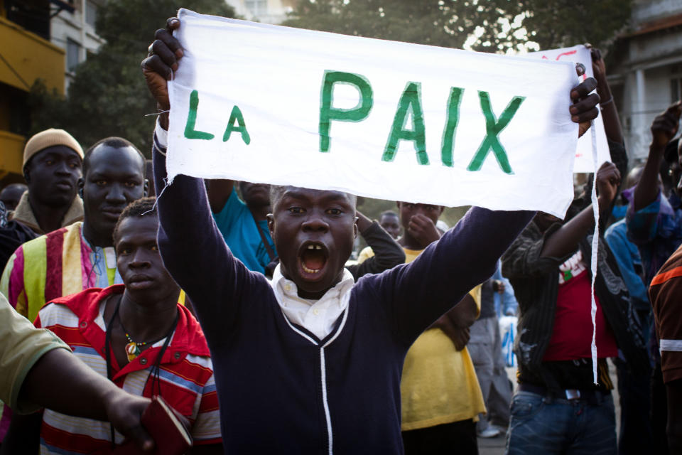 A boy holds a sign reading 'Peace' as people gather for a planned anti-government protest in central Dakar, Senegal Wednesday, Feb. 22, 2012. Thousands of supporters turned out to see Senegalese President Abdoulaye Wade Wednesday as he held rallies in the downtrodden Pikine and Guediawaye suburbs. Daily protests have rocked the capital after the opposition vowed to render the country ungovernable if 85-year-old Wade runs for a third term in Sunday's elections.(AP Photo/Tanya Bindra)