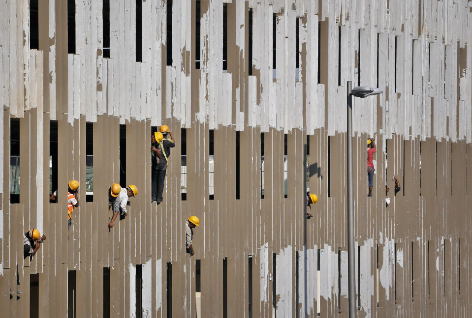 In this Wednesday, Jan. 8, 2014 photo, workers put final touches at the parking zone of the new airport terminal at the Chhatrapati Shivaji International Airport in Mumbai, India. India's overcrowded financial capital unveils its long-awaited $2 billion new airport terminal Friday, an ambitious, art-filled space that developers hope will be a showcase success in a country struggling to modernize inadequate infrastructure that is holding back economic growth. (AP Photo/Rajanish Kakade)