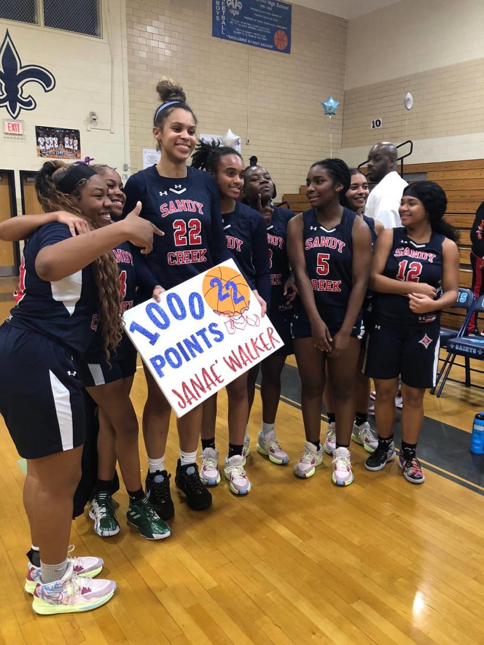 Janaé Walker (22) celebrates scoring her 1,000th career point with her high school teammates in February.