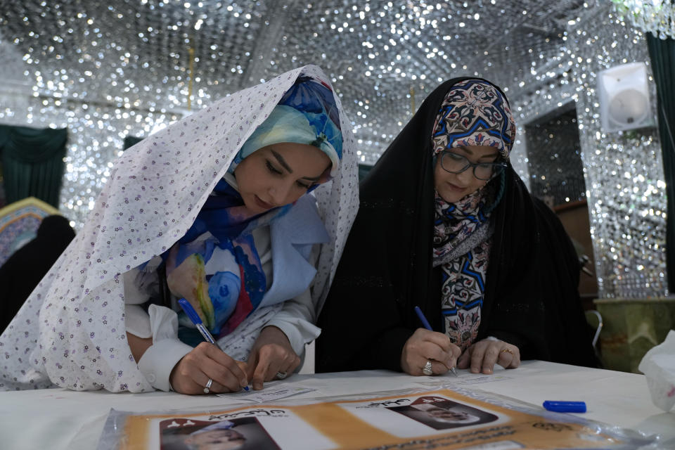 Women fill out their presidential election ballots in a polling station at the shrine of Saint Saleh in northern Tehran, Iran, Friday, July 5, 2024. Iran held a runoff presidential election on Friday that pitted a hard-line former nuclear negotiator against a reformist lawmaker. (AP Photo/Vahid Salemi)