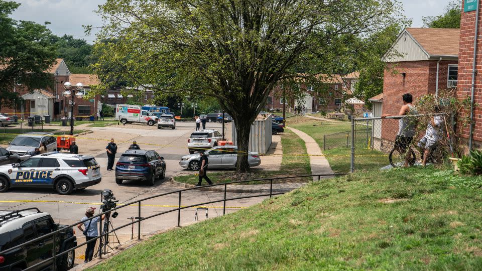 Residents watch as Baltimore police investigate the site of a mass shooting in the Brooklyn Homes neighborhood on July 2, 2023. - Nathan Howard/Getty Images