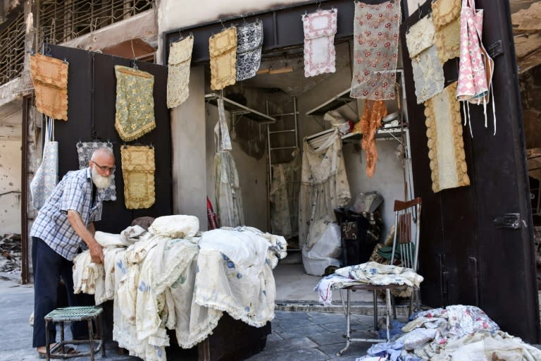 Mohammad Shawash arranges the display outside his shop in the Old City of Aleppo on July 22, 2017 amid the destruction caused by years of battles