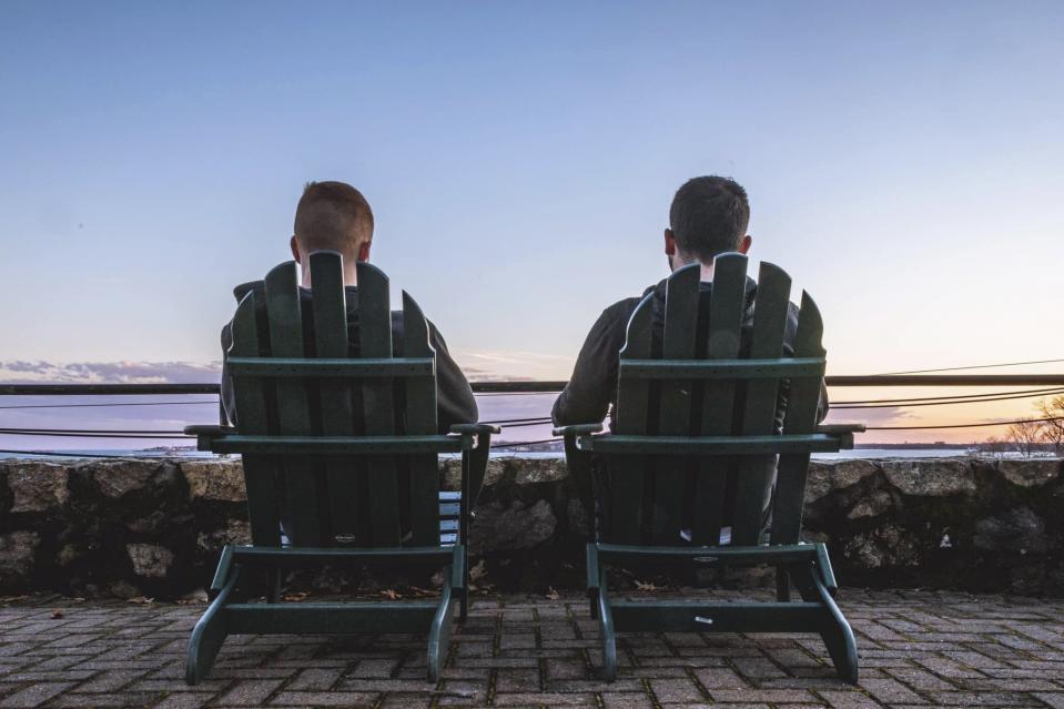 In this March 13, 2020, photo, Endicott College seniors Rob Ackerman, left, and Nick Grace sit on the school's campus in Beverly, Mass. Due to the coronavirus outbreak it's not clear whether the campus will reopen in time for graduation. The new coronavirus causes mild or moderate symptoms for most people, but for some, especially older adults and people with existing health problems, it can cause more severe illness or death. (Nick Grace via AP)