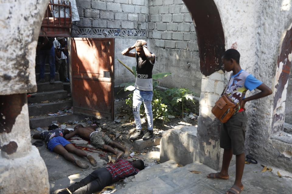 Dos personas observan los cadáveres de tres personas asesinadas a tiros durante una balacera nocturna en el vecindario de Pétion Ville, en Puerto Príncipe, Haití, el 1 de abril de 2024. (AP Foto/Odelyn Joseph)