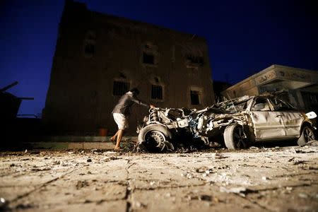 A man checks the wreckage of a car at the site of a car bomb attack in Yemen's catpital Sanaa June 17, 2015. REUTERS/Khaled Abdullah