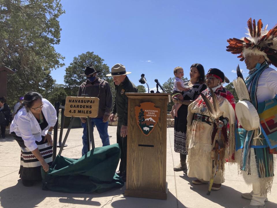 Members of the Havasupai Tribe and Grand Canyon National Park Superintendent Ed Keable, behind podium, unveil a sign marking the renaming of a popular campground from Indian Garden to Havasupai Gardens on Thursday, May 4, 2023 at the national park in northern Arizona. The site lies about 4.5 miles down the Bright Angel Trail in the canyon. (AP Photo/Felicia Fonseca)