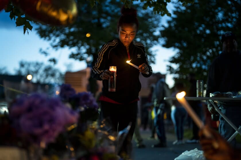 BUFFALO, NY - MAY 16: Alexis Rodriguez, of Buffalo, lights candles as people gather at the scene of a mass shooting at Tops Friendly Market at Jefferson Avenue and Riley Street on Monday, May 16, 2022 in Buffalo, NY. The fatal shooting of 10 people at a grocery store in a historically Black neighborhood of Buffalo by a young white gunman is being investigated as a hate crime and an act of "racially motivated violent extremism," according to federal officials. (Kent Nishimura / Los Angeles Times)