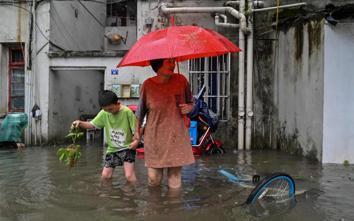 A woman and a boy wade in a flooded street in a neighbourhood in Ningbo, eastern China's Zhejiang province, as Typhoon In-Fa lashes the eastern coast of China - AFP