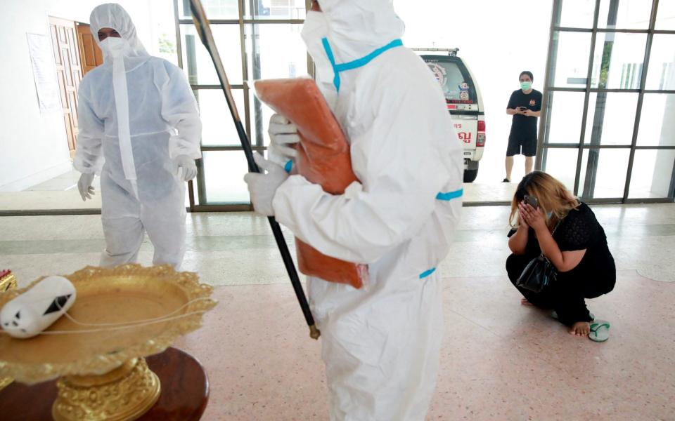 AA family member cries as Thai Buddhist monk Pongpetch Santijittho is seen wearing a protective suit over his robe to cremate the body of a coronavirus disease (COVID-19) victim at a temple in Pathumthani Province, near Bangkok, Thailand July 15, 2021. - Reuters