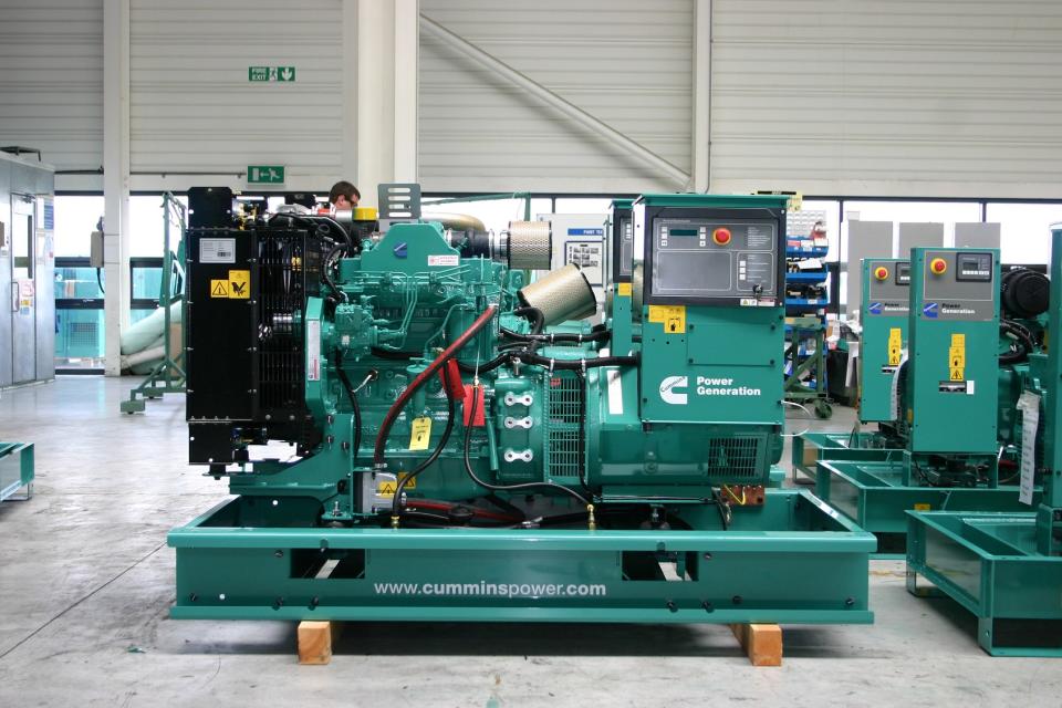 Green power generation equipment in a warehouse, with Cummins logo on it.