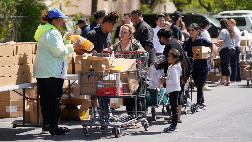 A Utah Food Bank volunteer loads groceries for a woman at a food bank distribution Friday, May 13, 2022, in Salt Lake City.