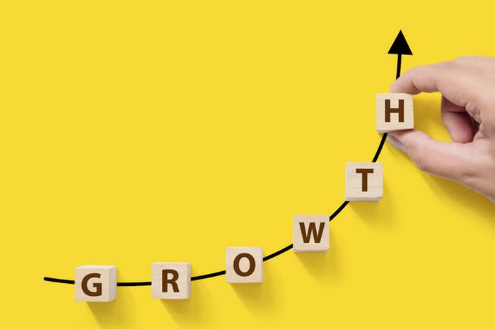 A hand placing blocks spelling out the word growth along a rising graph.