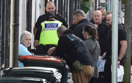 A woman speaks to police officers standing outside a house being searched after three men were arrested in connection with an explosion on the London Underground, in Newport, Wales, Britain, September 20, 2017. REUTERS/Rebecca Naden