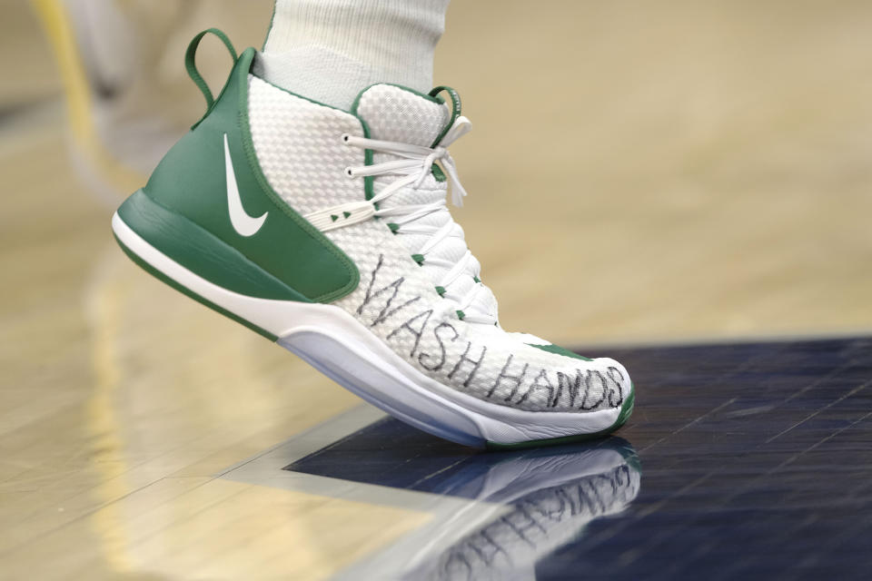 Boston Celtics center Enes Kanter wears shoes with "wash hands" written on them during the second half of the team's NBA basketball game against the Indiana Pacers in Indianapolis, Tuesday, March 10, 2020. The Celtics won 114-111. (AP Photo/AJ Mast)