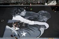 Fans polish the mural in memory of Kobe Bryant and his daughter Gianna