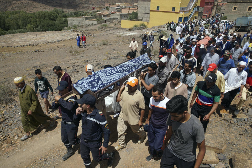 Security forces carry the body of a man who died in a flash flood in Tizert, near the southern region of Taroudant, Morocco, Thursday, Aug. 29, 2019. Morocco's official MAP news agency says that seven people watching a local soccer match in a southern village have died in a flash flood that swept across a football field on Wednesday evening. (AP Photo/Mohamed Amerkad)
