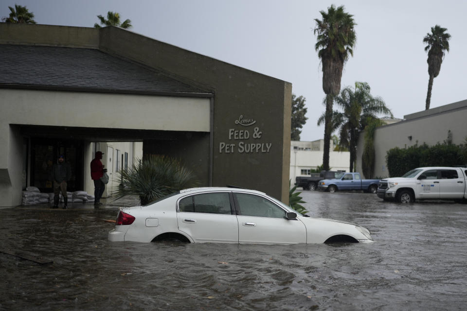 A vehicle is submerged in front of a feed and pet supply store during a rain storm, Thursday, Dec. 21, 2023, in Santa Barbara, Calif. (AP Photo/Jae C. Hong)