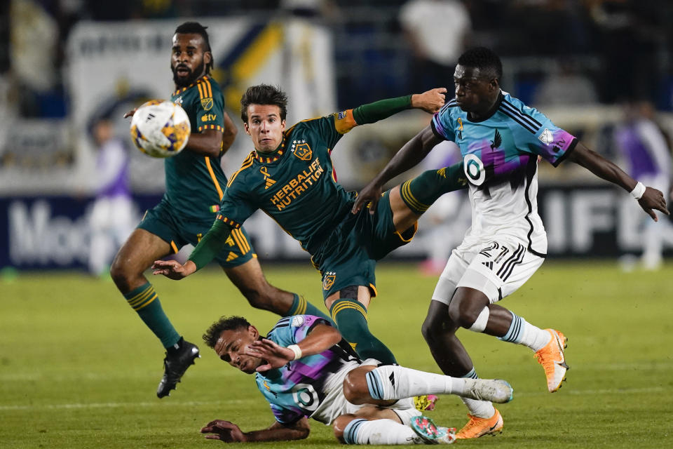 LA Galaxy midfielder Riqui Puig, center, shoots over Minnesota United midfielder Hassani Dotson, bottom, as United forward Bongokuhle Hlongwane closes in during the second half of an MLS soccer match Wednesday, Sept. 20, 2023, in Carson, Calif. (AP Photo/Ryan Sun)