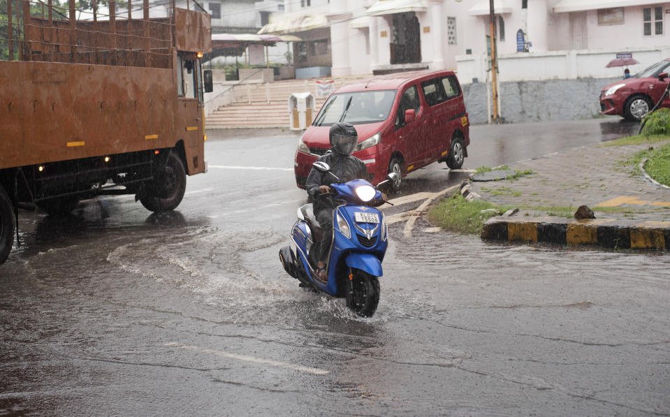 A man rides his scooter during heavy rainfall in Kochi, Kerala state, India, Friday, Aug. 7, 2020. A mudslide triggered by heavy monsoon rain and flooding killed at least five people in the state on Friday, police said. (AP Photo/R S Iyer)