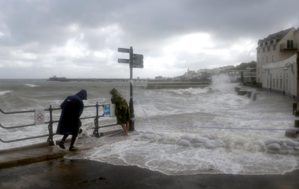 People watch as waves crash along the coast at Swanage in Dorset on Friday as Storm Alex hitPA