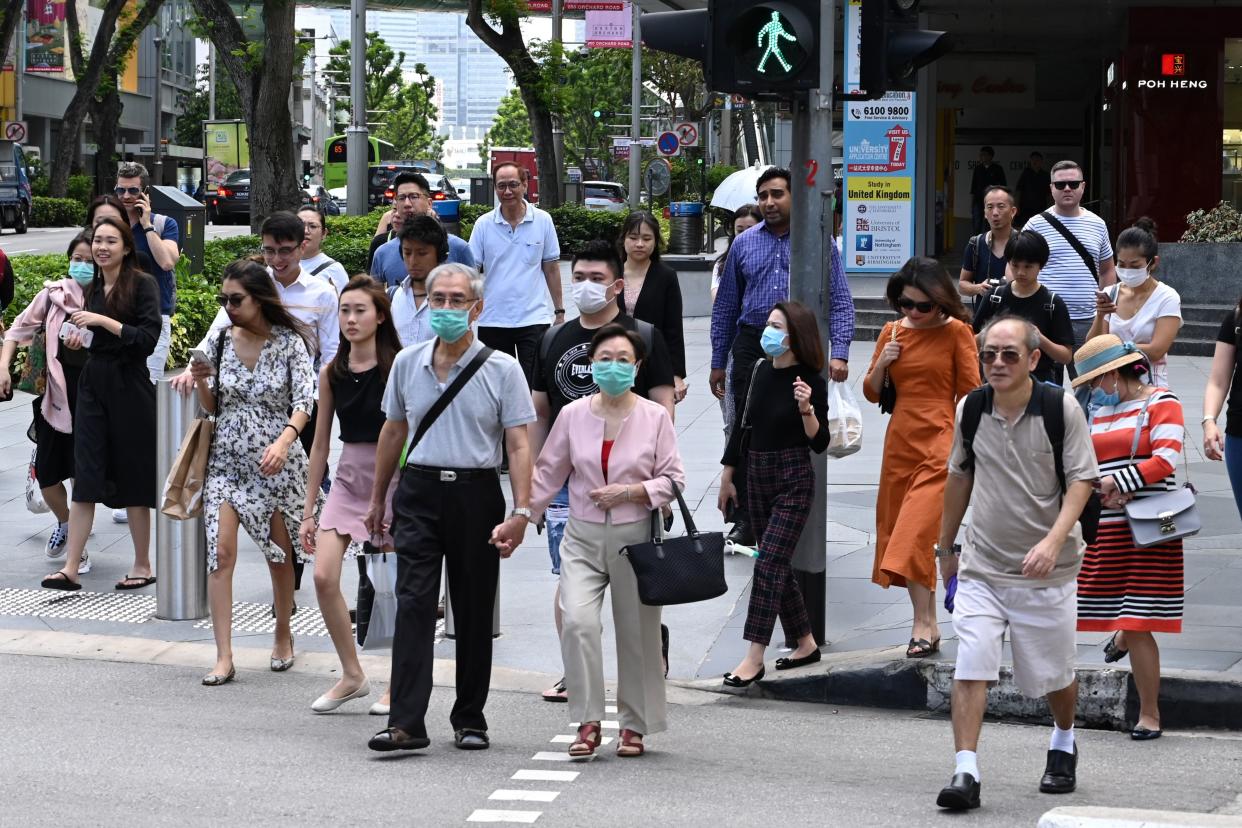 People, some wearing a protective facemask amid fears about the spread of the COVID-19 novel coronavirus, crosses the road in Singapore on February 26, 2020. (Photo by Roslan RAHMAN / AFP) (Photo by ROSLAN RAHMAN / AFP) (Photo by ROSLAN RAHMAN/AFP via Getty Images)