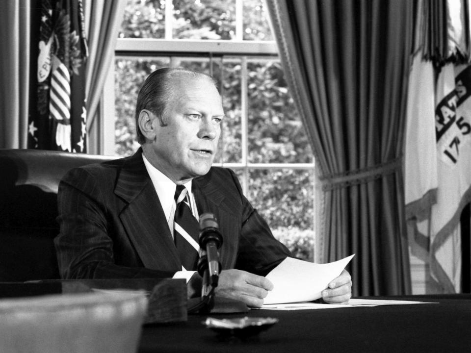 President Gerald Ford, while sitting at the desk in the Oval Office, announced his decision to grant a pardon to former President Richard Nixon in 1974.