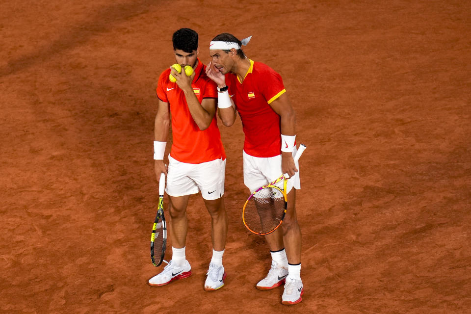 Carlos Alcaraz, left, talk with Rafael Nadal from the Spanish team during the men's doubles tennis competition against Andres Molteni and Maximo Gonzalez from the Argentina team, at the 2024 Summer Olympics, Saturday, July 27, 2024, in Paris, France. (AP Photo/Manu Fernandez)