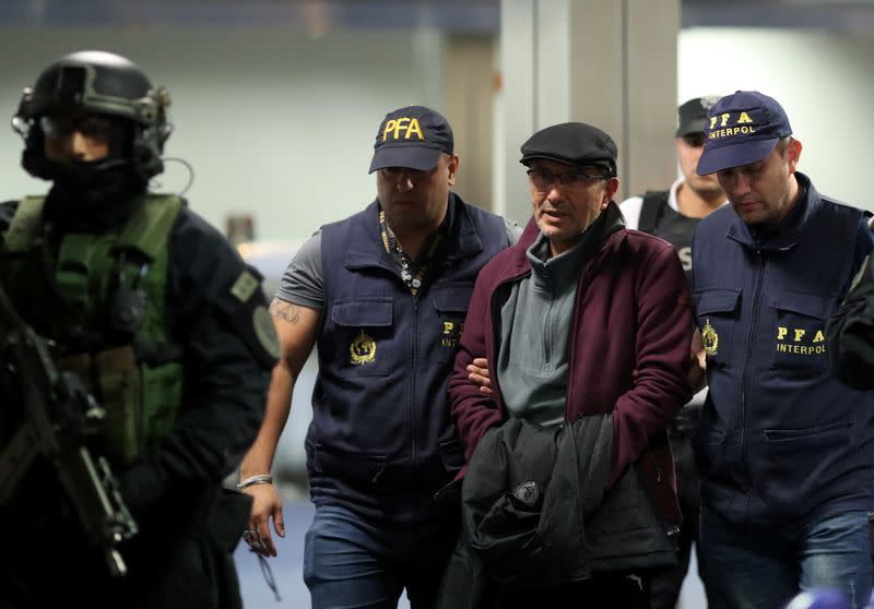 Mario Sandoval is escorted by police officers after being extradited from France, in Buenos Aires