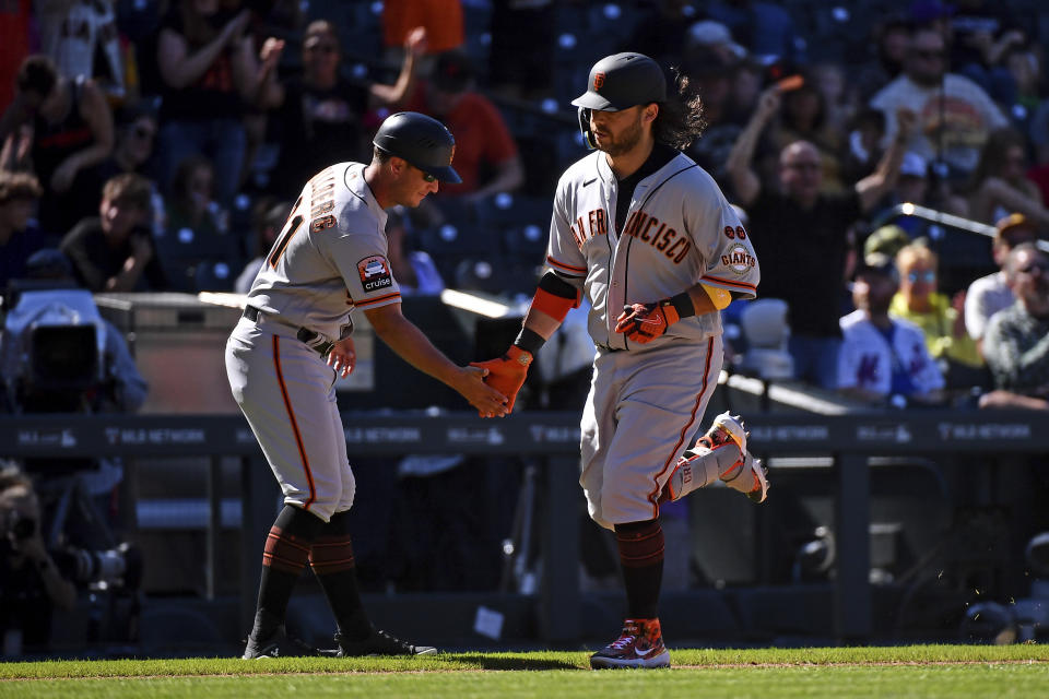 San Francisco Giants third base coach Mark Hallberg, left, and Brandon Crawford celebrate a home run in the sixth inning of a baseball game against the Colorado Rockies, Sunday, Sept. 17, 2023, in Denver. (AP Photo/Geneva Heffernan)