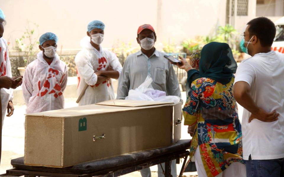 Relatives stand beside a coffin containing body of a victim who died with Coronavirus in Hyderabad, Pakistan - NADEEM KHAWAR/EPA-EFE/Shutterstock