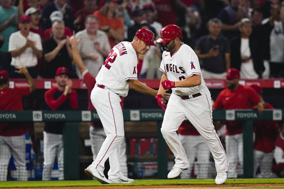 Los Angeles Angels' Mike Moustakas is congratulated by third base coach Bill Haselman (82) after hitting a three-run home run against the San Francisco Giants during the sixth inning of a baseball game Wednesday, Aug. 9, 2023, in Anaheim, Calif. (AP Photo/Ryan Sun)