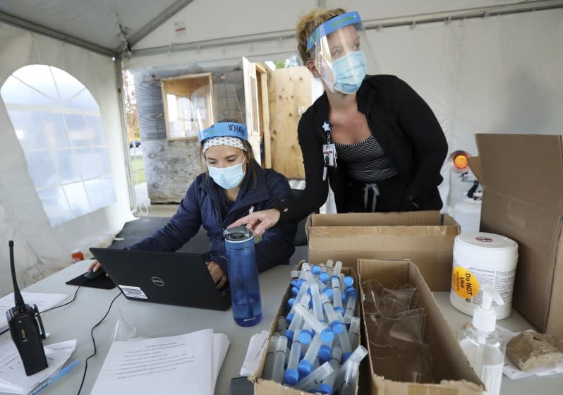 Nursing assistant Monica Brodsky, left, and nurse Taylor Mathisen work at a drive-thru testing site for COVID-19 in the parking lot at UW Health Administrative Office Building in Middleton, Wis., Monday, Oct. 5, 2020. A surge of coronavirus cases in Wisconsin and the Dakotas is forcing a scramble for hospital beds and raising political tensions, as the Upper Midwest and Plains emerge as one of the nation's most troubling hotspots. (Amber Arnold/Wisconsin State Journal via AP)