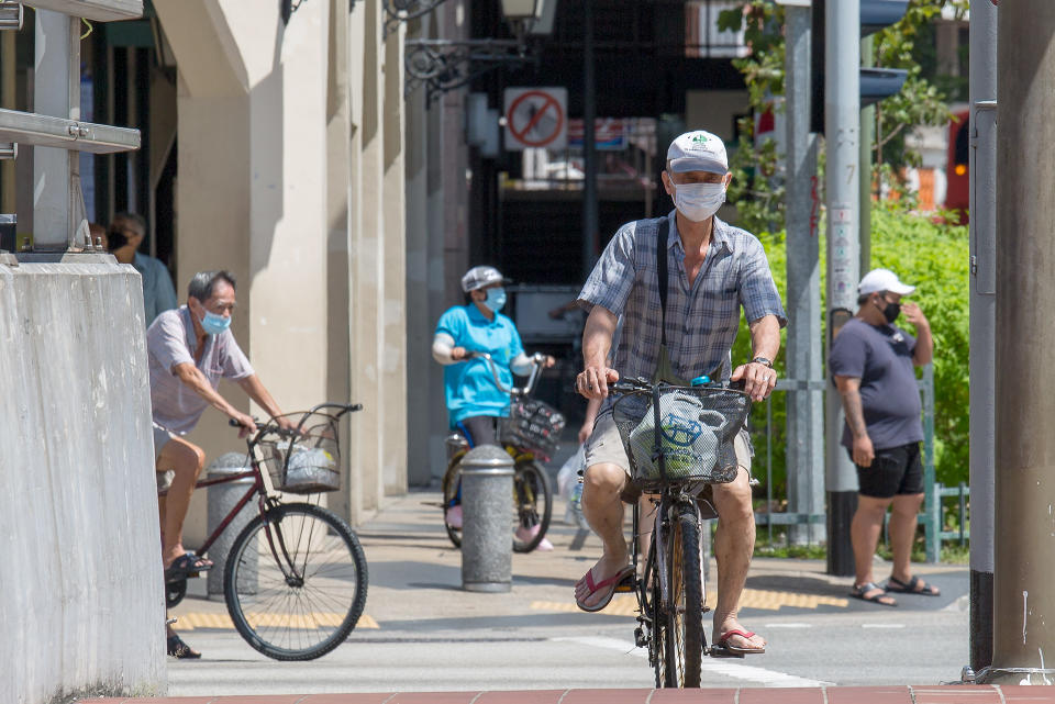 Men in face masks seen riding bicycles around the Eu Tong Sen Street on 21 April 2020, the 15th day of Singapore's partial lockdown. (PHOTO: Dhany Osman / Yahoo News Singapore)