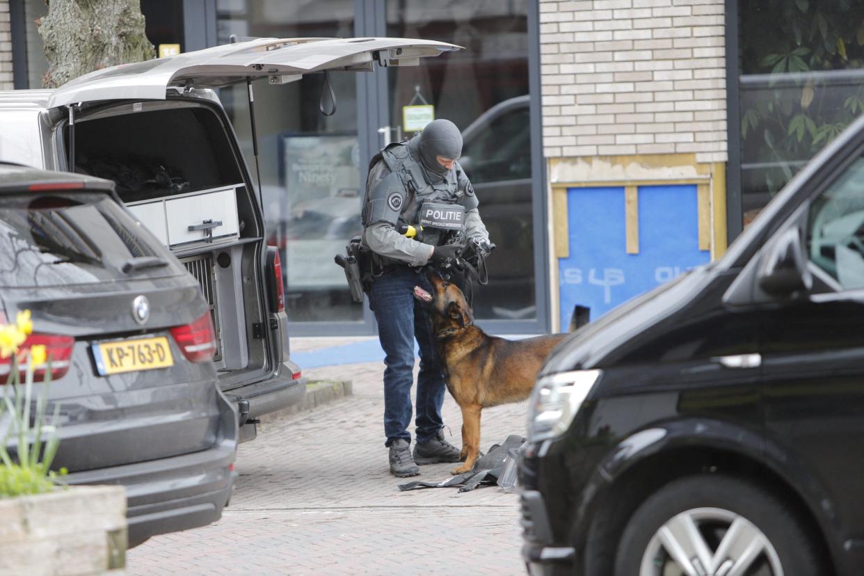 An armoured police officer handles a police dog near the Cafe Petticoat (Luciano de Graaf via REUTERS)