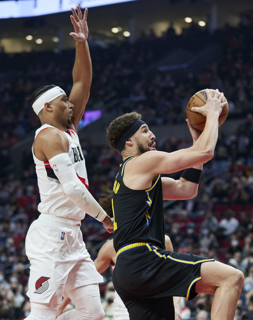 Golden State Warriors guard Klay Thompson, right, shoots in front of Portland Trail Blazers guard Josh Hart during the first half of an NBA basketball game in Portland, Ore., Thursday, Feb. 24, 2022. (AP Photo/Craig Mitchelldyer)