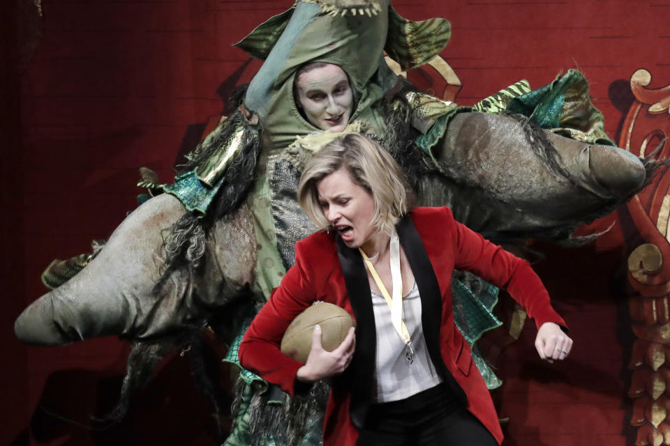 Actor and director Elizabeth Banks plays football against an actor in a dragon costume as she is honored as the 2020 Woman of the Year by Harvard University's Hasty Pudding Theatricals, Friday, Jan. 31, 2020, in Cambridge, Mass. (AP Photo/Elise Amendola)