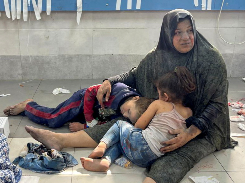 A Palestinian woman holds her children, who were wounded along with her in an Israeli strike, at Al-Shifa hospital in Gaza City on Monday (REUTERS)