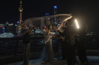 A veil is thrown over a bride as she has her wedding photos taken on the bund in Shanghai, Wednesday, July 31, 2024. (AP Photo/Ng Han Guan)