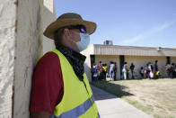 Dave, right, who declined to give his last name, from Toledo, Ohio, wears a neon vest as migrants are processed by a humanitarian group after being released from U.S. Customs and Border Protection custody, Friday, Sept. 24, 2021, in Del Rio, Texas. Dave, who has been to Haiti many times, befriended a woman named Ruth, who he believes is still in custody after she crossed the Rio Grande with her husband and their 3-year-old daughter. Dave drove down from Ohio to Southwest Texas in hopes of picking the family up and driving them to Ohio, where Ruth has family awaiting them. (AP Photo/Julio Cortez)