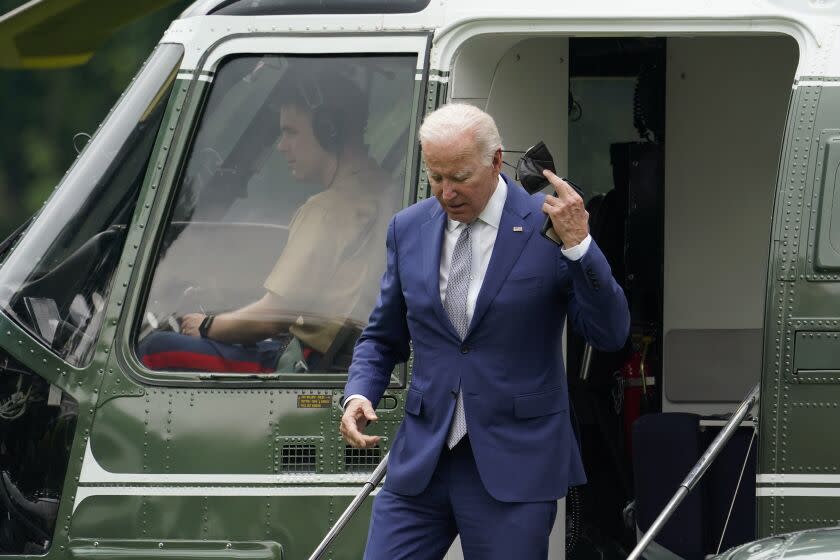 President Joe Biden removes his mask as he steps off Marine One on the South Lawn of the White House, Tuesday, June 14, 2022, in Washington. Biden is returning to Washington after speaking at the AFL-CIO convention in Philadelphia. (AP Photo/Patrick Semansky)