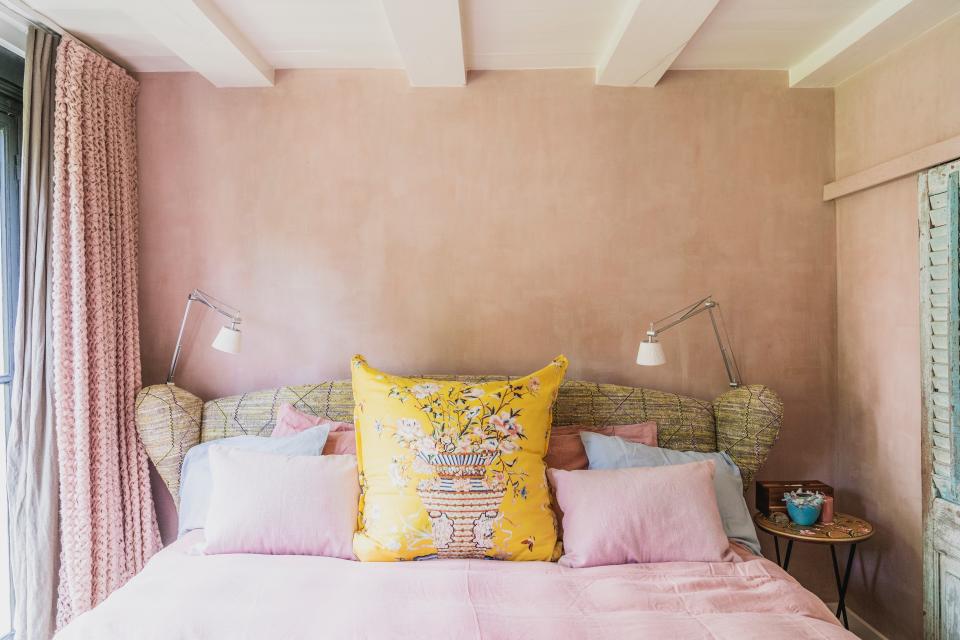 “I advise my clients to choose two curtains for the bedroom: one that keeps the sunlight out and one that’s see-through,” Madelon notes. The curtains in this bedroom are an army green linen from Lizzo and a pink fabric from Sahco. The pink walls are a nod to Tuscany.