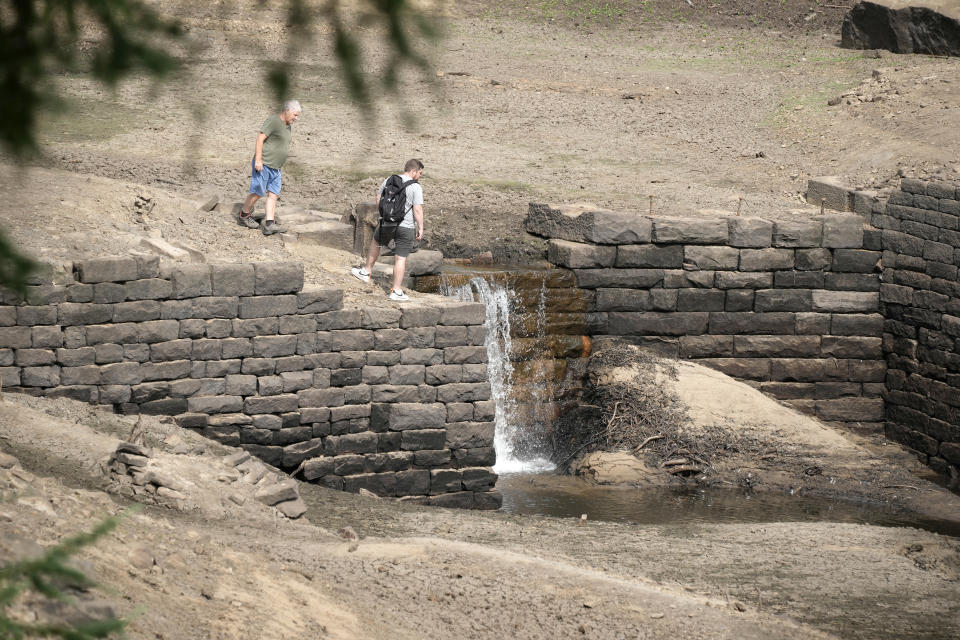 HARROGATE, ENGLAND - JULY 19: People walk along the reservoir bed after water levels in the Thruscross reservoir are partially depleted in the heatwave on July 19, 2022 in Harrogate, England. Yorkshire Water, the regional utility, warned residents to use water wisely during the heatwave, adding that the area has had below average rainfall since last autumn. (Photo by Christopher Furlong/Getty Images)