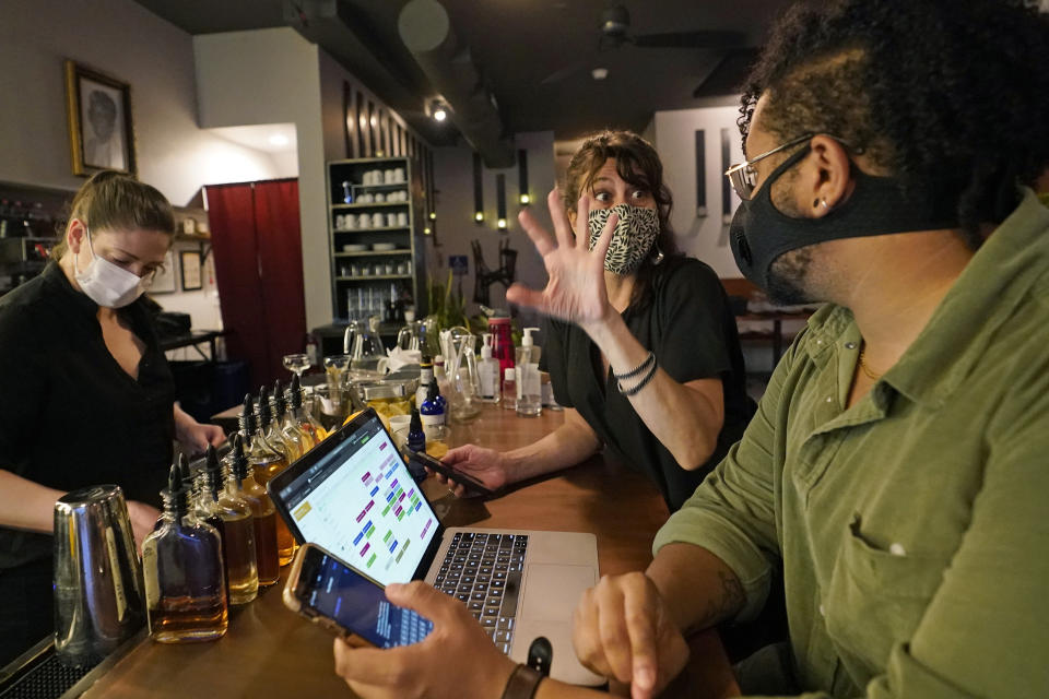 Mama Fox bar and restaurant owner Samantha DiStefano, center, discusses her indoor dining reopening plans with manager Akin Payne, right, as bartender Devon Schickling, left, prepares drinks for outdoor diners, Tuesday, Sept. 29, 2020, in New York. DiStefano and her staff are preparing to serve patrons indoors for the first time since the pandemic halted indoor restaurant service in March. (AP Photo/Kathy Willens)