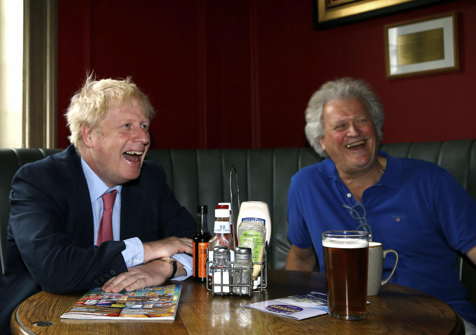 Conservative Party leadership candidate Boris Johnson, left, reacts with Tim Martin, Chairman of JD Wetherspoon, during a visit to Wetherspoons Metropolitan Bar in London, Wednesday July 10, 2019. (Henry Nicholls/Pool Photo via AP)