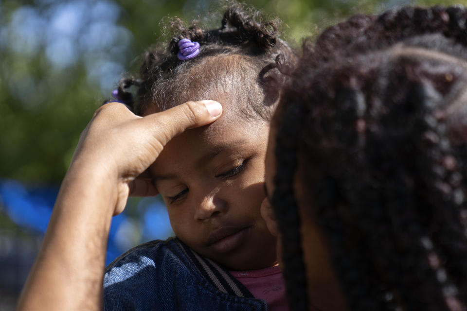 Anmani Rendon of Venezuela feels the forehead of her 2-year-old daughter Sofia Barragan outside of the 12th District police station where migrants are camped, Saturday, Oct. 7, 2023, in Chicago. (AP Photo/Erin Hooley)