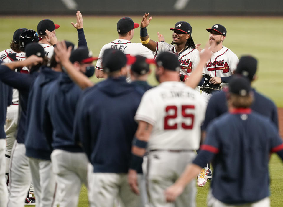 Atlanta Braves' Ronald Acuna Jr., right, and the team celebrates after a baseball game to clinch the NL East title against the Miami Marlins on Tuesday, Sept. 22, 2020, in Atlanta. (AP Photo/Brynn Anderson)