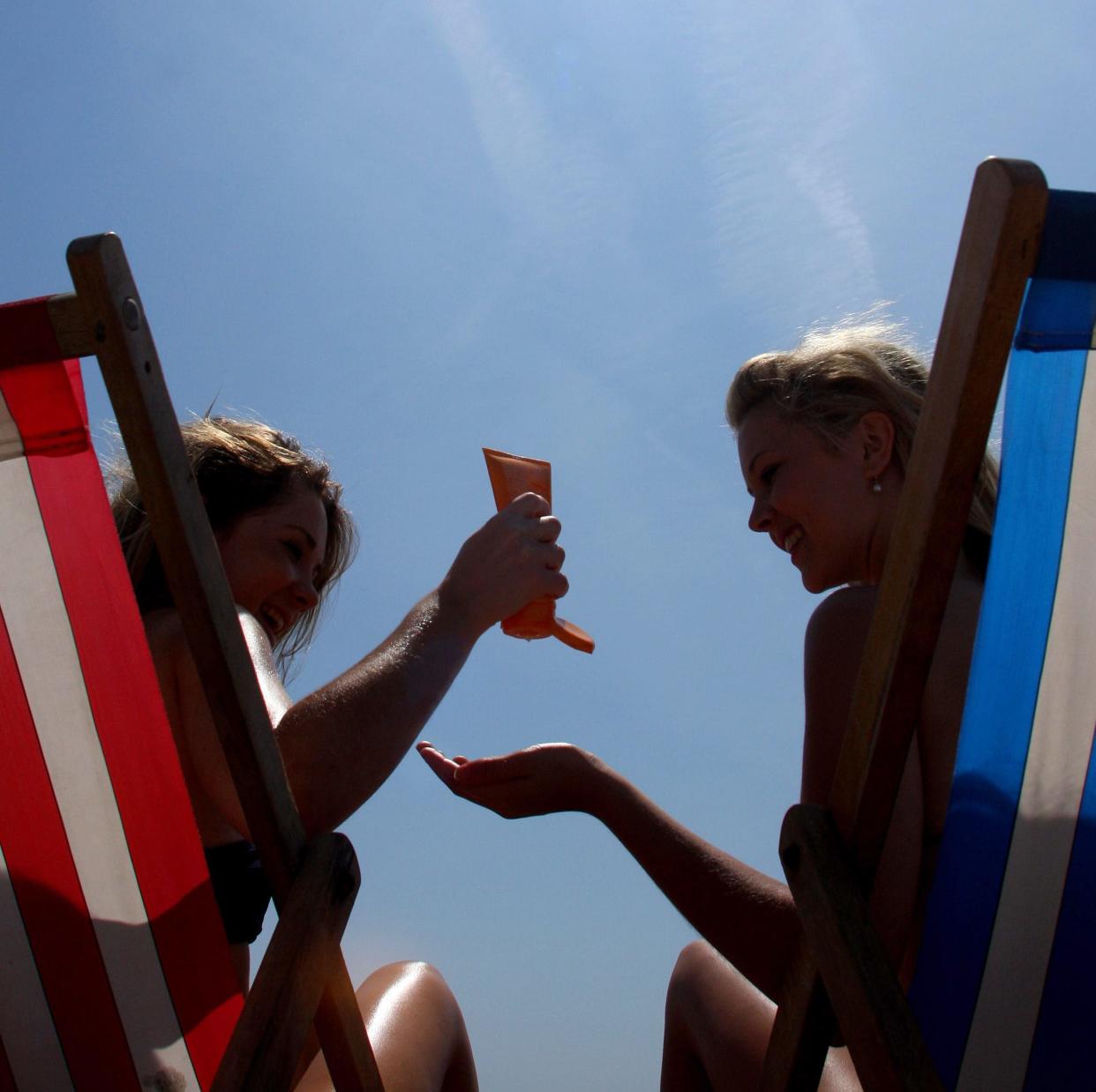 two sunbathers applying sun cream on a beach - Copyright (c) 2009 Rex Features. No use without permission.