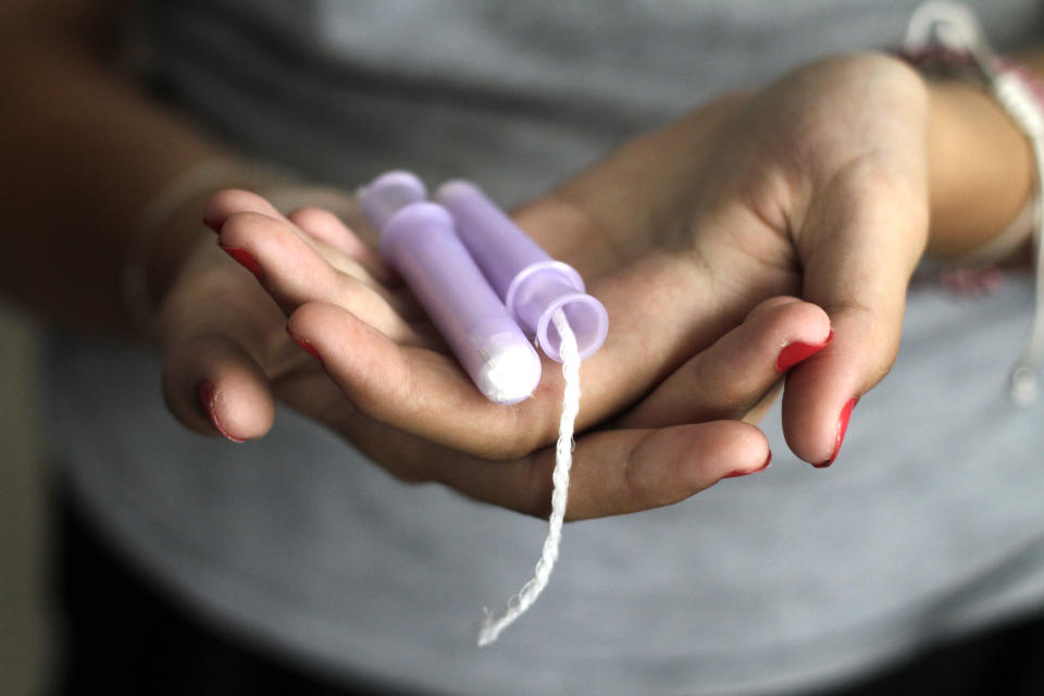 A close-up of a person holding a purple tampon in their palms